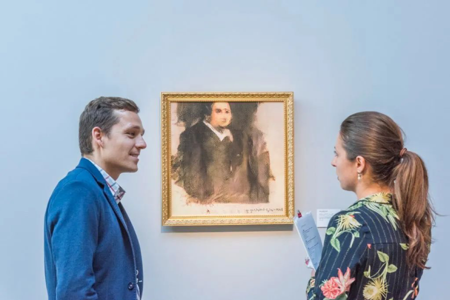 Two people looking at a painting on a wall
Description automatically generated